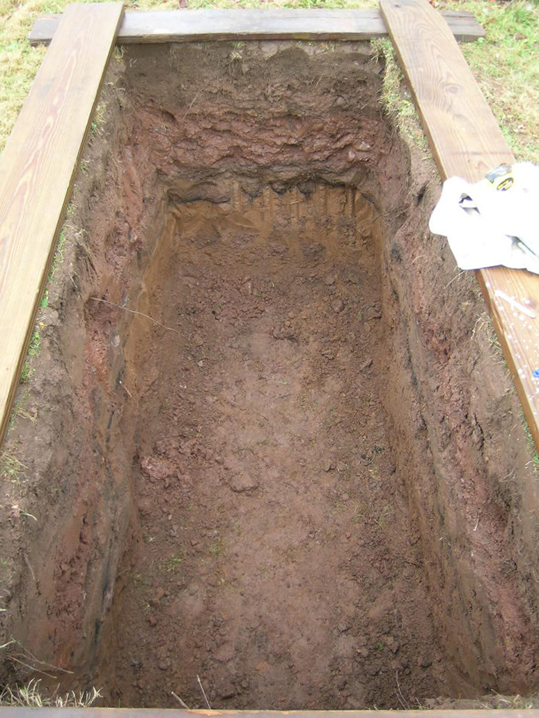 Looking into an empty grave cut in the African Burying Place at Hillside Cemetery. The stratigraphy shows a prior burial already existed here.