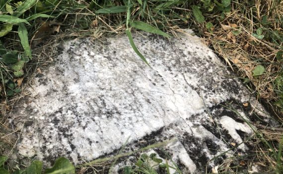 A piece of Henry Freeman's headstone embedded in the ground.